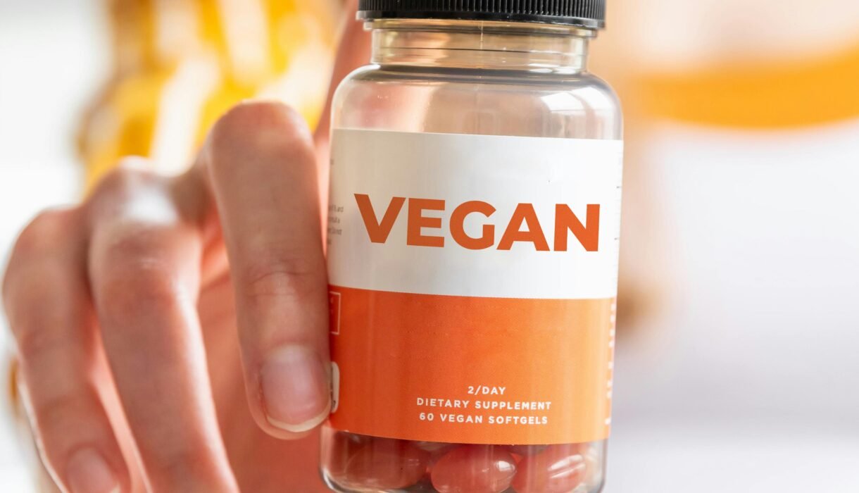 A detailed image of a hand holding a vegan supplement bottle, ideal for health and lifestyle themes.