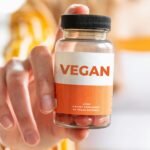 A detailed image of a hand holding a vegan supplement bottle, ideal for health and lifestyle themes.